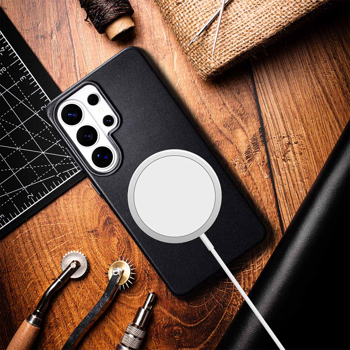 Black S26 Ultra Leather phone case with a Magsafe on a wooden surface with Leather Craftsmanship tools.
