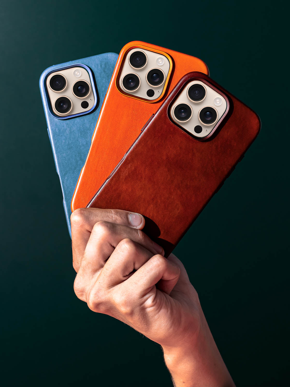 Three Vintage Luxe leather phone cases, held in hand