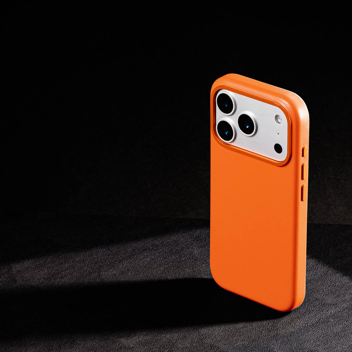 iphone 17 pro leather case in solar orange - raised camera ring and colour matched metal buttons detailing