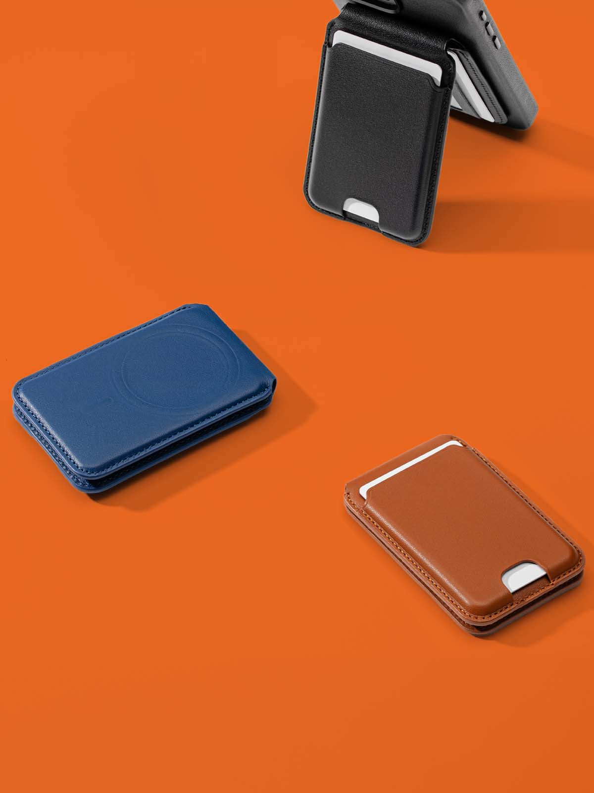 Three MagSafe-compatible leather kickstand wallets in black, blue, and tan, displayed on an orange background.